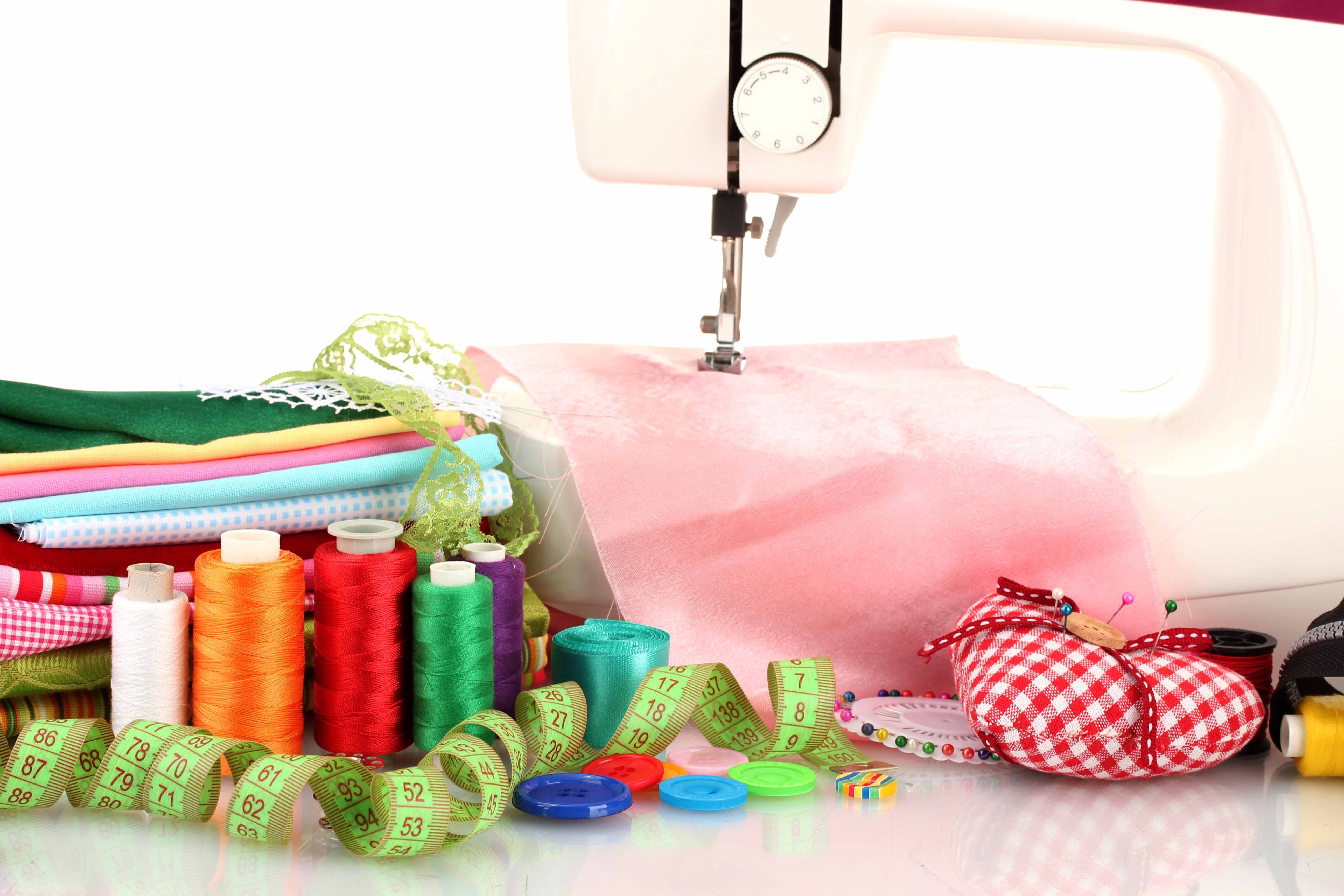 Sewing. Швейные принадлежности. Принадлежности для шитья и рукоделия. Швейная машинка с тканью. Фон с рукодельными принадлежностями.